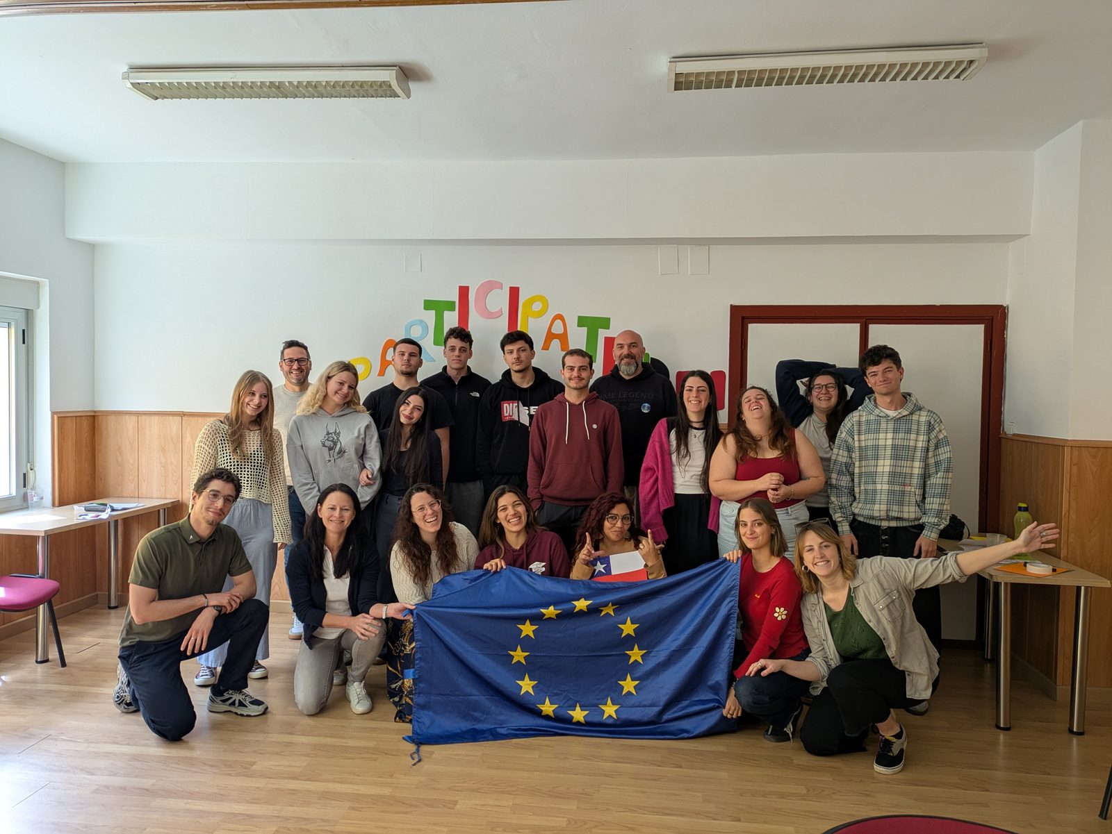 Young Erasmus+ participants from EVEC Athens and partner organisations holding the EU flag at the June 2026 youth project in Spain