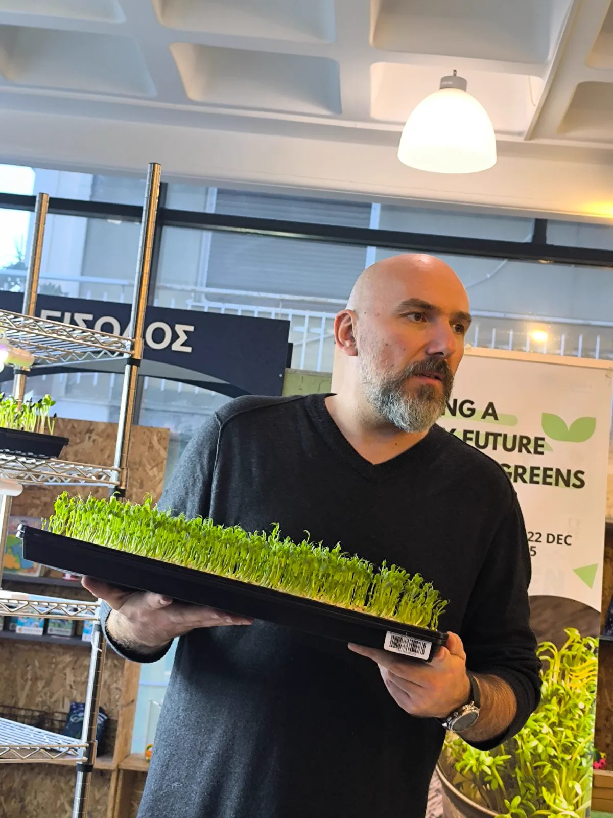 An EVEC trainer holding a freshly grown tray of microgreens