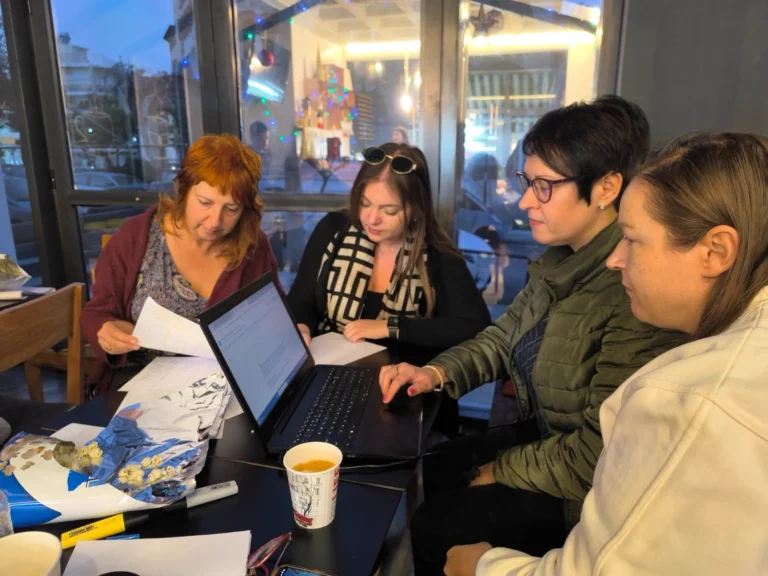 Four participants work together over a laptop and handwritten notes during an EVEC training course in Athens