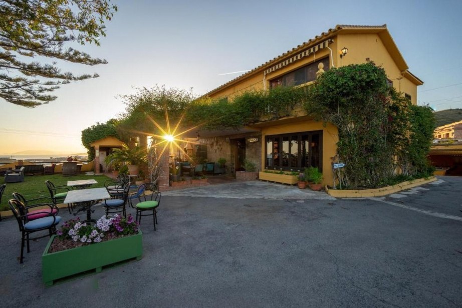 The yellow Andalusian country house of Cortijo Amaya, covered in climbing plants, with garden tables in front