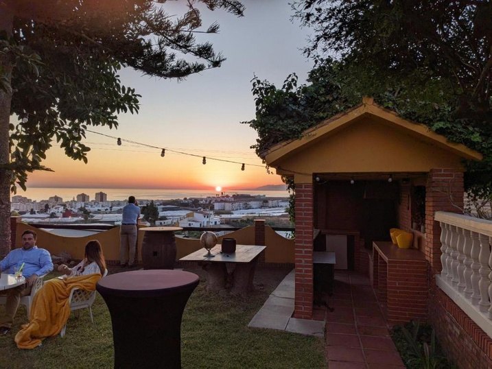 Garden terrace of Cortijo Amaya at sunset, with string lights and a view over Torrox-Costa to the sea