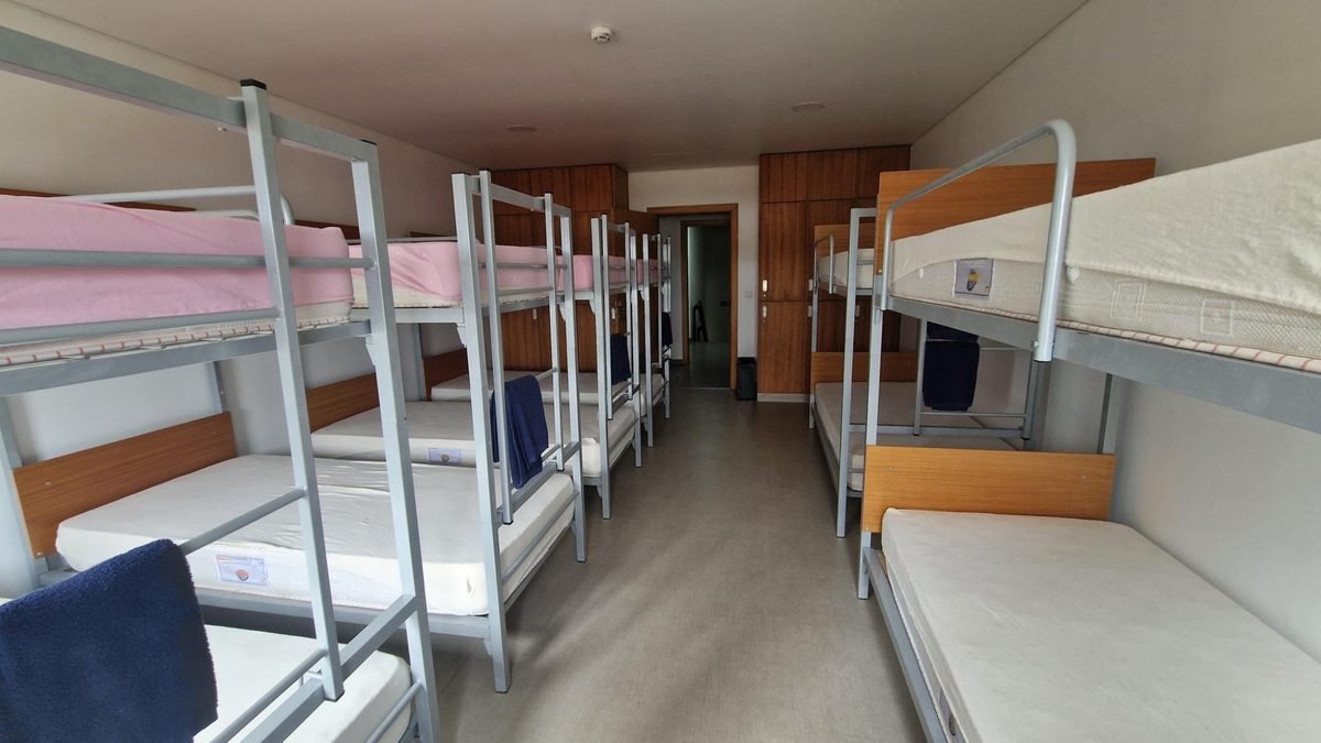 Long dormitory at the Scout Centre on Terceira, with rows of grey metal bunk beds, white mattresses and wooden headboards