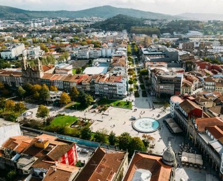 Aerial view of central Braga, with its main square, fountain and red-tiled roofs, and green hills behind