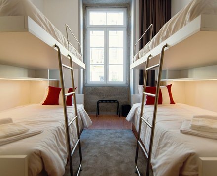 Shared room at the Braga Youth Centre with bunk beds, white bed linen and red pillows