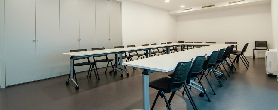 Bright training room at the Braga Youth Centre with long white tables and black chairs